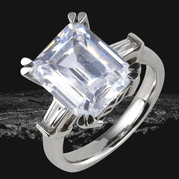 Billionaire Ring in sterling silver with rhodium plating, featuring a large emerald-cut gemstone and tapered baguette accents, designed for female jewelry collectors.