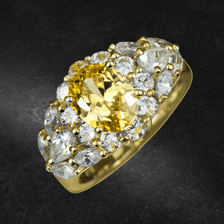 Gold Canaria Ring featuring a sterling silver band with gold plating, showcasing a central yellow gemstone surrounded by clear sparkling stones, designed for women’s jewelry collection.