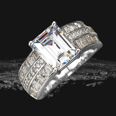Aldelphi Ring featuring a large emerald-cut center stone set in sterling silver with rhodium plating, accented by multiple smaller sparkling stones, designed for women’s jewelry.