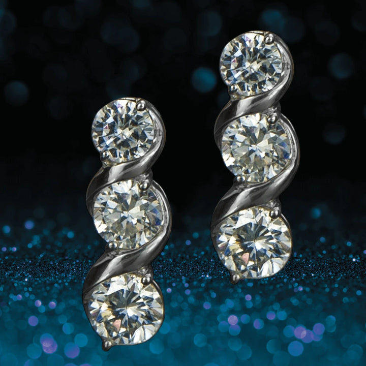 Solitaire Twist Earrings featuring three sparkling stones each, set in sterling silver with rhodium plating for a luxurious, elegant female jewelry piece.