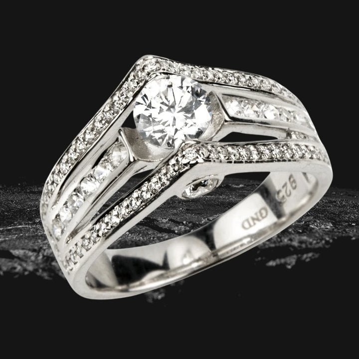 Point Ring for female made of sterling silver with rhodium plating, featuring a central gemstone surrounded by radiant smaller stones in an elegant design.