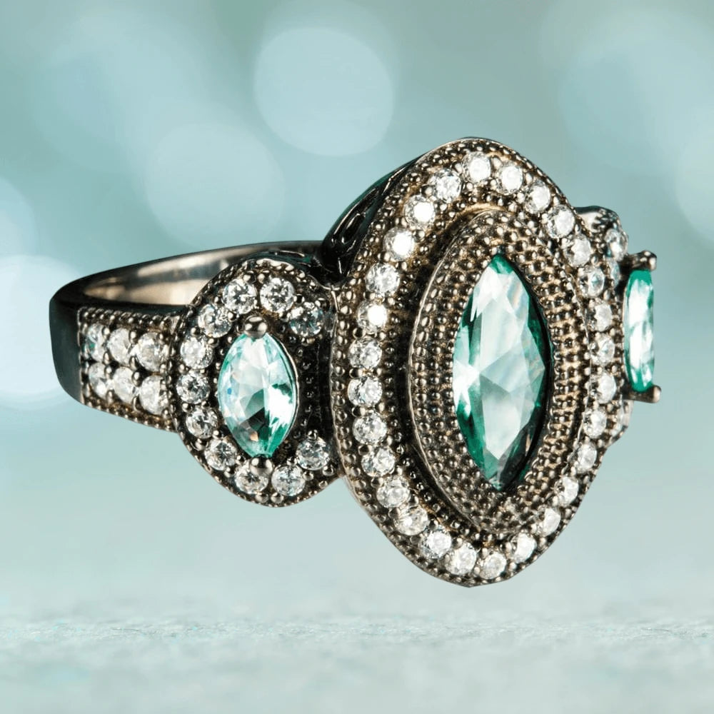 Black Orchid Ring in sterling silver featuring a central marquise-cut aqua gemstone surrounded by two rows of small clear stones, designed for female jewelry lovers.