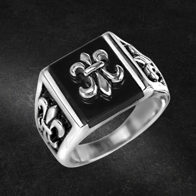 Grand Canyon Steel Ring featuring a bold stainless steel design with a black square face and intricate fleur-de-lis patterns, crafted for men’s jewelry collections.