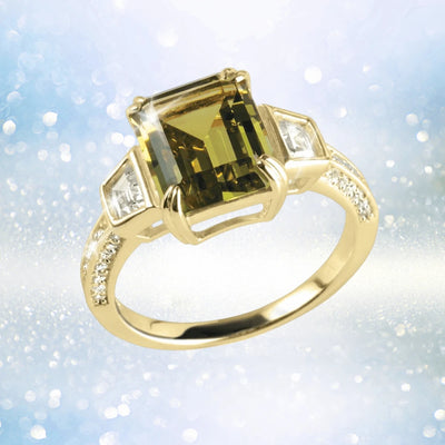 Lucia Ring featuring a sterling silver band plated in gold with a large rectangular green gemstone centerpiece and smaller clear gemstones accenting the sides, designed for female jewelry enthusiasts.