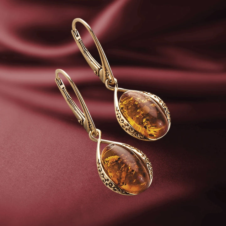 Baltic Amber Earrings featuring teardrop-shaped amber stones set in intricate gold-plated sterling silver, designed for elegant female jewelry collections.