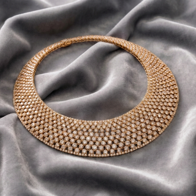 Riviera Gold Necklace featuring a white base metal with gold plating, intricately designed with sparkling stones, displayed on soft gray fabric, elegant jewelry for female.
