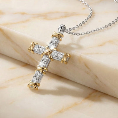 Gold and silver cross pendant necklace on a marble surface