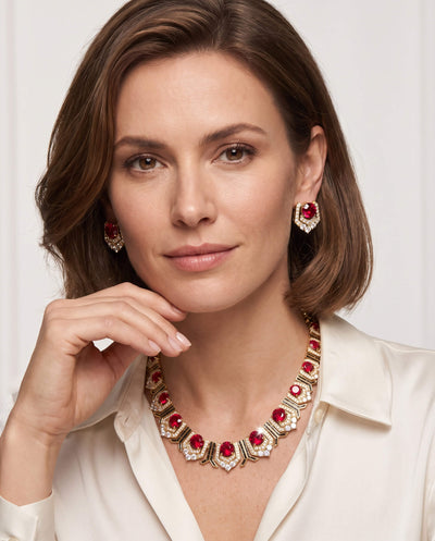 Woman wearing an elegant Scarlet Heirloom Necklace featuring red gemstones and gold accents, paired with matching earrings, promoting jewelry Up To 75% Off Retail.