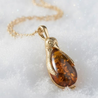 Gold necklace with a amber pendant on a white background. Penguin Baltic Amber Pendant