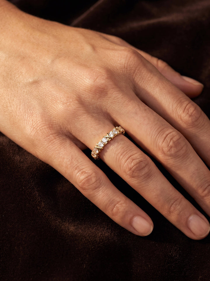 Golden Kiss Ladies Ring with a sparkling gold band and clear stones worn on a hand against dark satin Up To 75% Off Retail