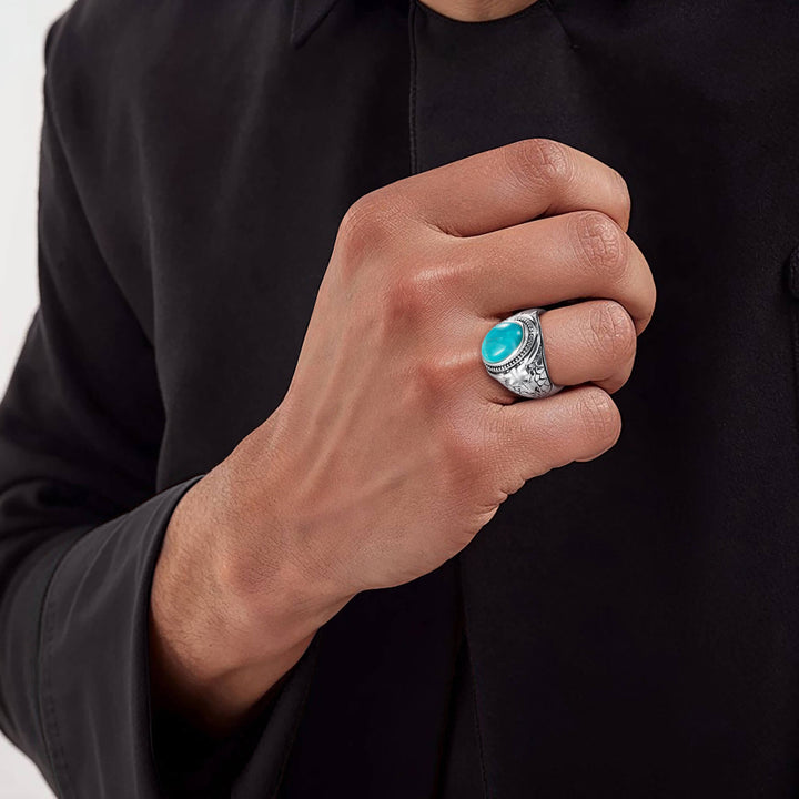 Hand wearing a turquoise stone ring with a black shirt background