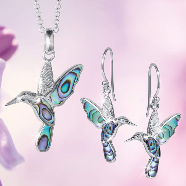 Silver hummingbird pendant and earrings with blue and green abalone inlays, over a pink flower pattern