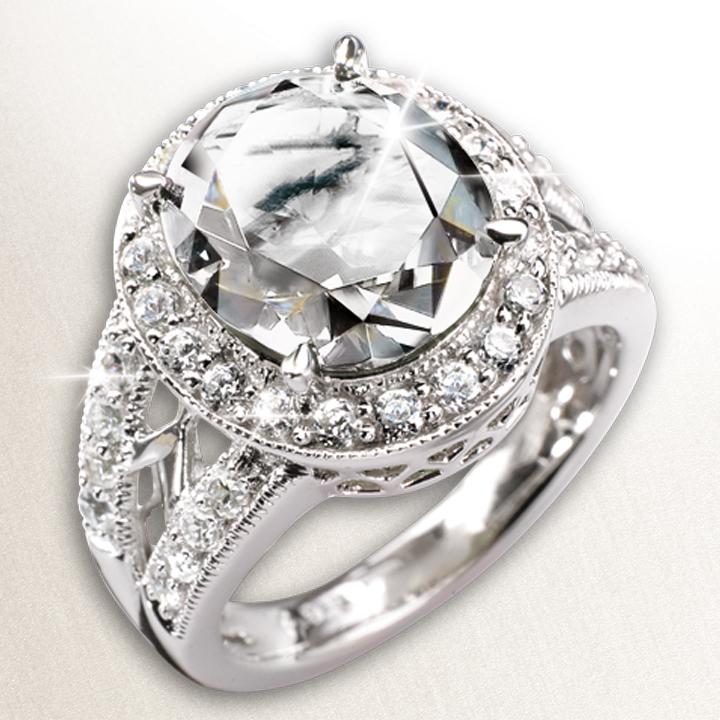 Millionaire Oval Clear Ring featuring a large clear oval stone set in sterling silver with rhodium plating, adorned with smaller sparkling stones for a luxurious, elegant look.