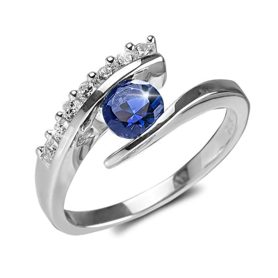 Eva Blue Ring featuring a sterling silver band with rhodium plating, showcasing a striking blue gemstone accentuated by small clear stones, designed for women’s jewelry collection.